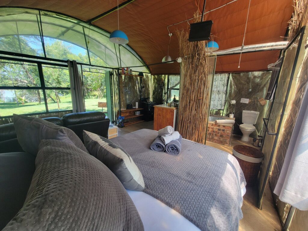 Wide interior view of the river hut showing bed, lounge and kitchen in one open space