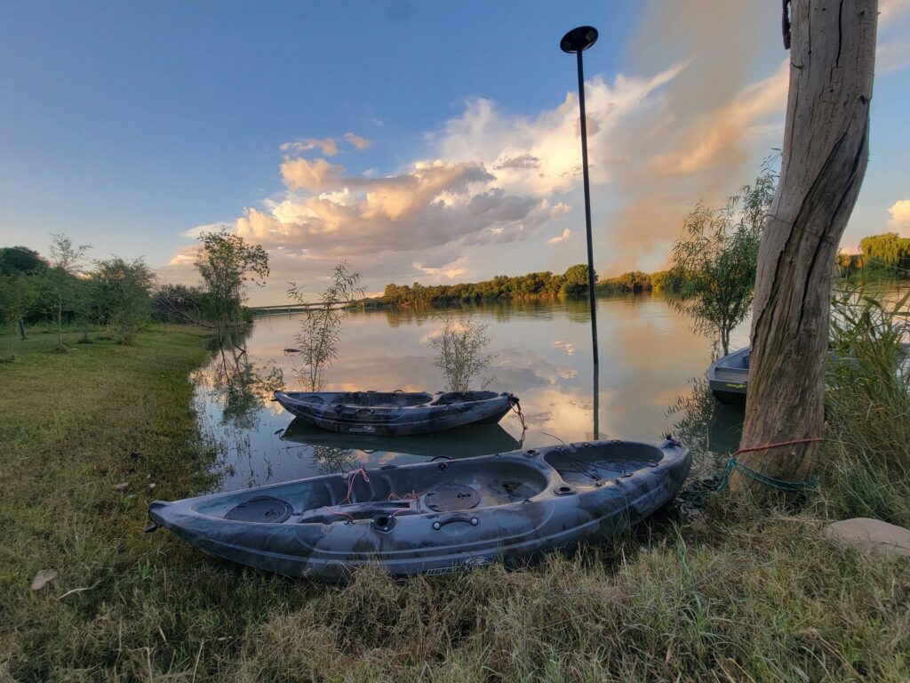 Two kayaks on the bank of the Orange River at golden hour, ready for guests to use