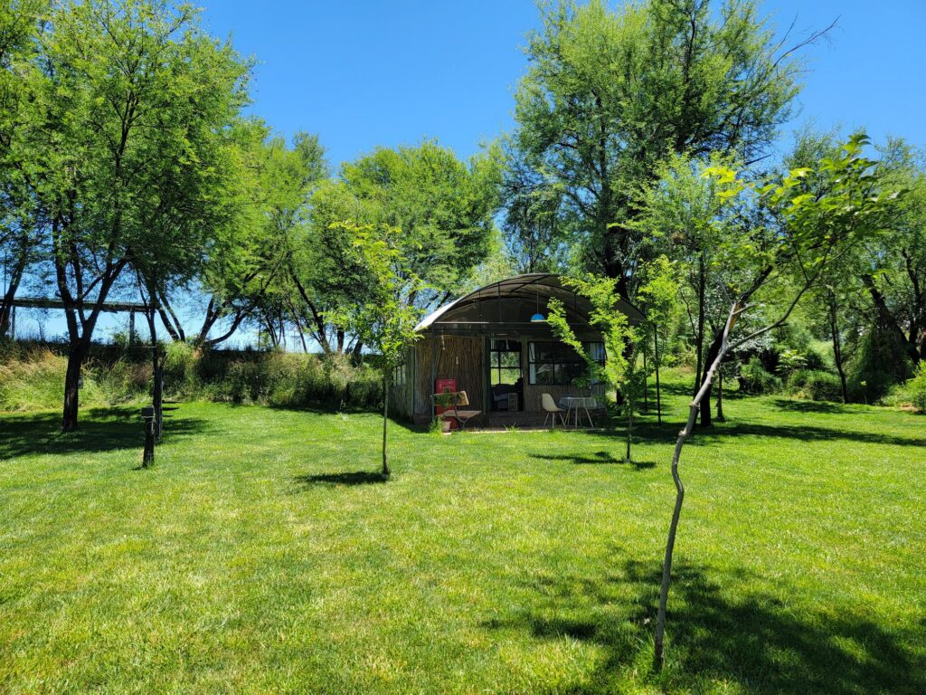 Wide lawn with the river hut tucked among willow trees at Wilger Rus Orania