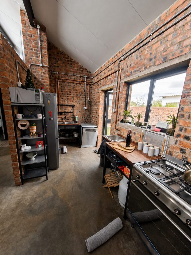 Kitchen with open shelving, a gas stove and a long counter under a face-brick wall