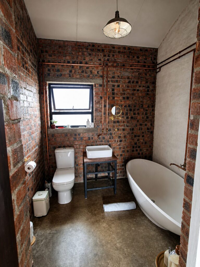 Main bathroom with a freestanding bath, basin and toilet against face-brick walls